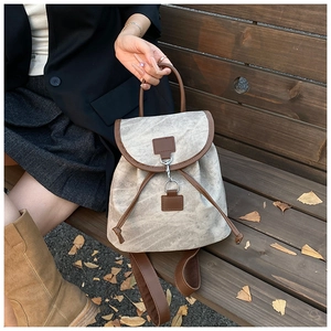 Detail view of canvas and leather retro backpack with metal hook clasp on wooden bench