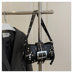 Detail of a punk style black leather bag featuring silver rivets and metal buckles