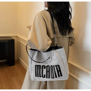 Silver glitter tote bag with MCADIA logo worn on shoulder showing large capacity and drape