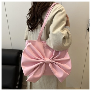 Borsa tote rosa con grande fiocco indossata a spalla da una modella femminile
