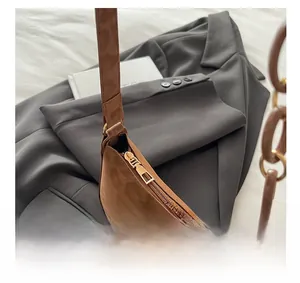 Detail of smooth metal zipper and silver bow decoration on brown suede underarm bag