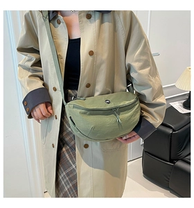 Detail of pea green crossbody chest bag in nylon fabric with OK logo on model