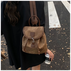 Outdoor street view of a vintage brown canvas backpack with leather trim on model