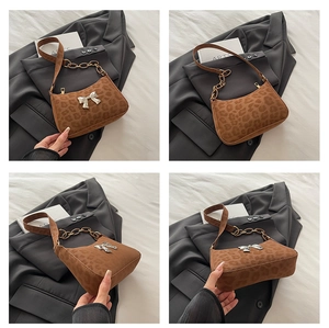 Detail of leopard print shoulder bag featuring a silver bow and dual metal chain straps
