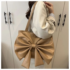 Detail of a large khaki tote bag featuring a prominent decorative bow and PU leather texture