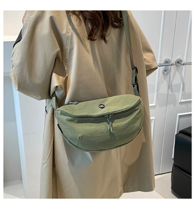 Detail of sage green nylon saddle bag with circular OK patch and adjustable strap