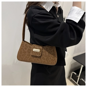 Détail d'un sac baguette léopard marron avec boucle dorée porté par un mannequin