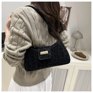 Détail du sac porté épaule noir à motif léopard avec fermoir en métal doré sur un modèle
