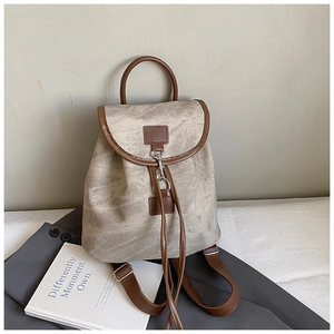 Detailed view of retro canvas backpack with brown leather trim and metal hook closure