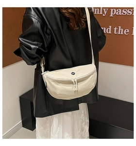 Detail view of cream nylon saddle bag with ok logo on model with black leather jacket