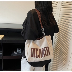 Model view of cream canvas tote bag with brown leather straps and metal chain detail