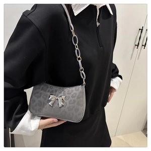 Detail of grey leopard print shoulder bag with silver butterfly buckle and chain strap