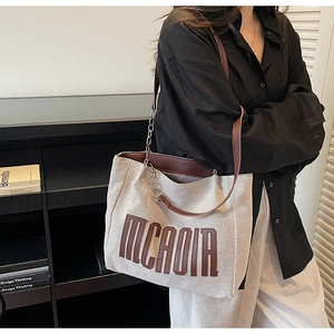 Detail of canvas tote bag with 3D MCAOIA letters and leather chain shoulder strap