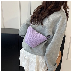 Detail of hand-woven purple crochet bucket bag with an elegant pearl button closure