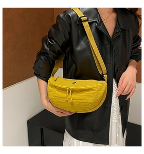Detailed close-up of yellow pleated crossbody bag showing textured fabric and strap