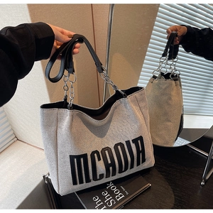Detail of woven tote bag with MCADIA lettering and silver chain strap attachment
