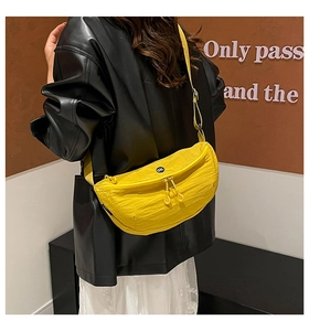 Detail of yellow nylon crescent bag with adjustable strap and small logo on model