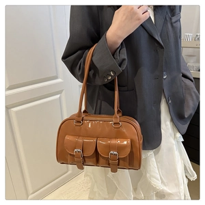 Detailed view of brown glossy leather bowling bag with functional dual front flap pockets