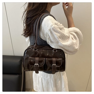 Detail of dark brown patent leather shoulder bag with dual front pockets and silver buckles