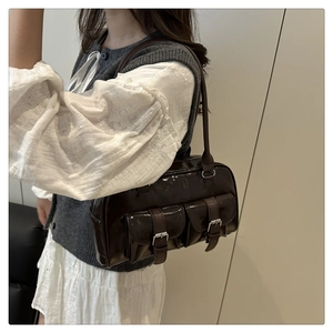 Detail of dark brown glossy shoulder bag featuring dual front pockets and silver buckles