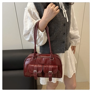 Detail of burgundy leather bowling bag featuring front pockets and silver buckles