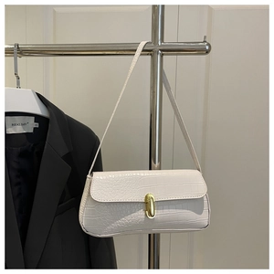 Detail of white crocodile embossed texture leather and golden metal clasp on a handbag