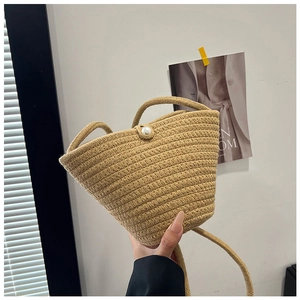 Detail of beige hand-woven bucket bag featuring a round pearl button closure and rope strap
