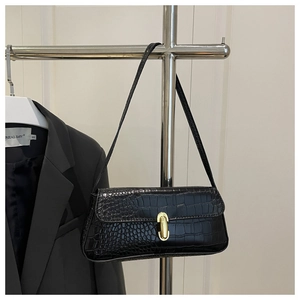 Detail of black crocodile texture leather underarm bag with gold oval twist lock