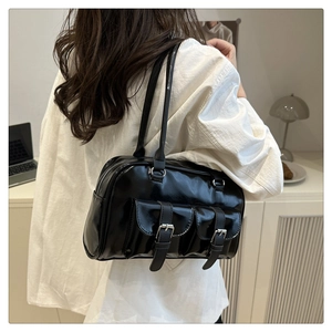 Close-up of black glossy leather shoulder bag with silver buckle pockets and dual straps