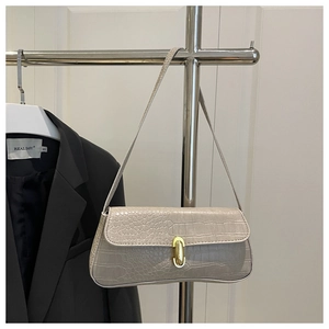 Detail of grey crocodile pattern shoulder bag featuring a gold twist lock and flap design