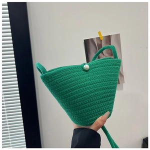 Detail of green handmade woven bucket bag featuring a large pearl clasp closure
