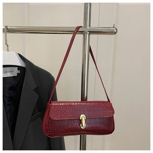Detailed view of crocodile pattern burgundy baguette bag with golden metal twist lock