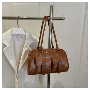 Close-up of retro brown glossy underarm bag with double buckle pockets on a silver hanger
