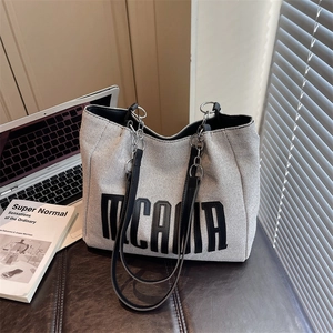 Fashionable woven tote bag with leather straps and metal chain in a minimalist urban setting