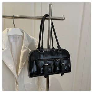 Detail of glossy black leather bowling bag with twin buckle pockets and silver metal hardware