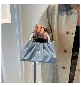 Detail of light blue pleated cloud bag featuring pearl handle and glossy leather finish