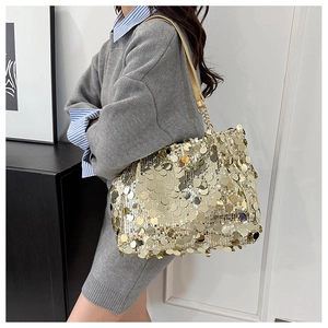 Gros plan d'un sac cabas à paillettes dorées avec chaîne porté par un mannequin