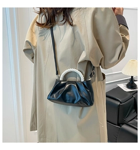 Detail of black pleated cloud bag featuring pearl handle and detachable shoulder strap