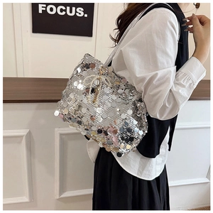 Close-up of a silver sequin tote bag featuring a decorative white pearl bow charm