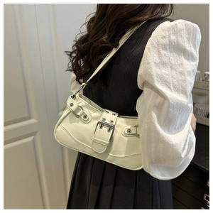 Close-up of cream-colored faux leather underarm bag with oversized buckle and metal studs