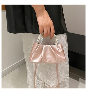 Detailed macro view of the pleated mini handbag with shiny rose gold pearl handle