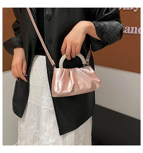 Detail of pearly pink pleated cloud bag with elegant pearl beaded handle and strap