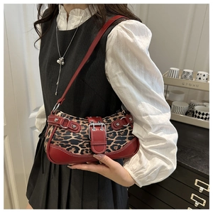 Detail of red leather and leopard print stitching with silver metal buckle on underarm bag