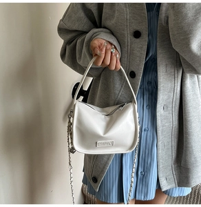 Détail de la texture en cuir PU blanc du sac à main avec bandoulière chaîne et écusson