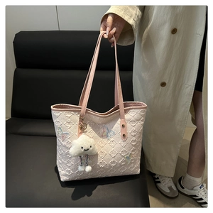 Dettaglio della borsa tote trapuntata con ricami di farfalle colorate e ciondolo nuvola