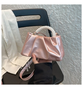 Detail of pink pleated mini bag with elegant large pearl handle and satin finish