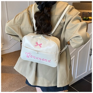 Detail of white bow backpack featuring pink embroidery in a lifestyle setting