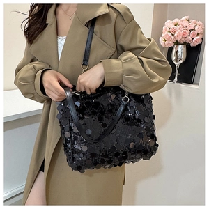 Détail d'un sac cabas noir à paillettes porté avec un trench pour un look tendance