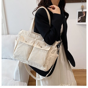 Detail der cremefarbenen Cord-Einkaufstasche mit Utility-Taschen und Trageriemen