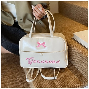 Detail of a creamy white bow backpack with pink embroidery and polished PU leather surface